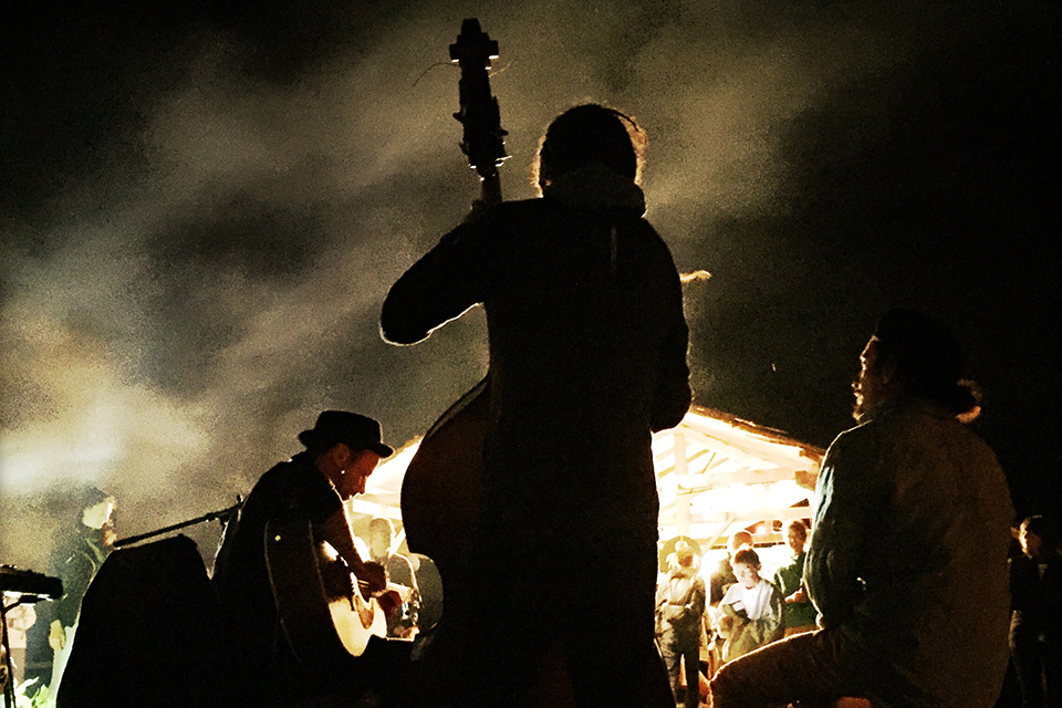 Das Bild zeigt drei Musiker mit Gitarre, Contrabass und Trommeln auf der Bühne.